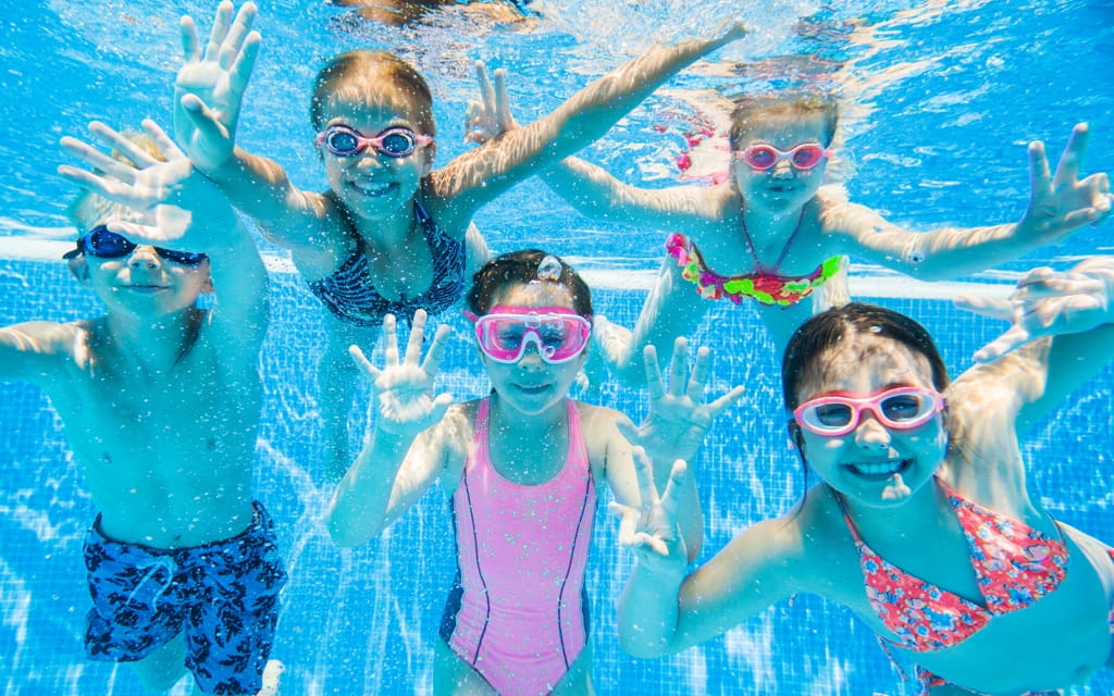 Kleine Kinder posieren unter Wasser während eines Schwimmkurses im Taubertsbergbad