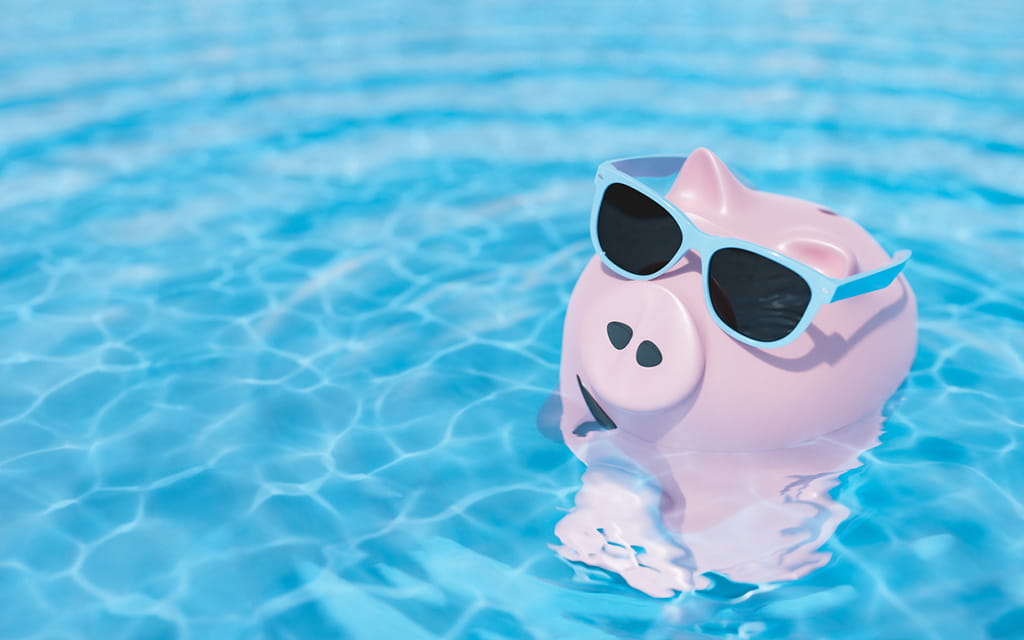 Rosa Sparschwein mit blauer Sonnenbrille im Pool