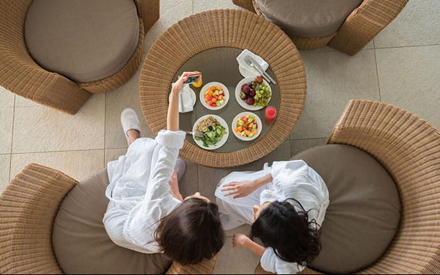 Zwei Damen sitzen im Gastronomie-Bereich und machen ein Selfie