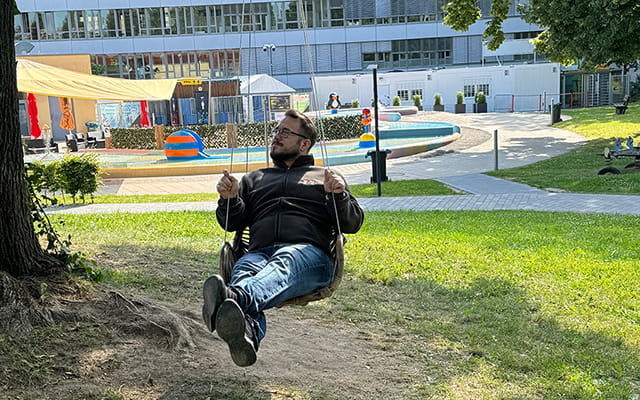 Mann sitzt auf einer Schaukel im Freibad