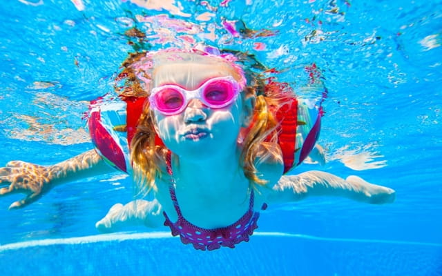 Unterwasseraufnahme eines kleinen Mädchens mit Schwimmflügeln repräsentiert den Kinderschwimmkurs in Mainz