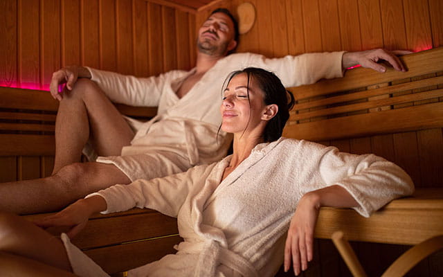 Ein Mann und eine Frau entspannen im Bademantel in der Sauna